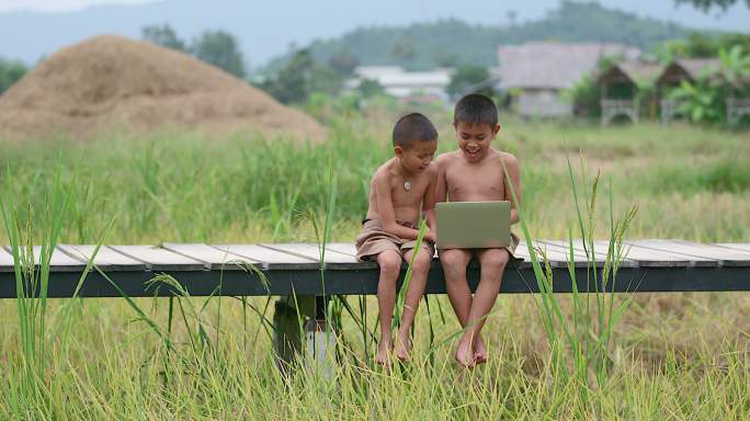 两个农村男孩快乐地玩着笔记本。