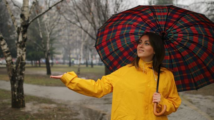 漂亮女孩打着伞在公园里散步