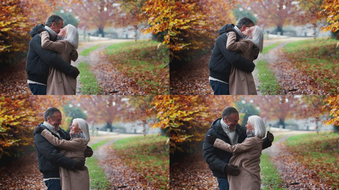 相爱的老年夫妇在秋天的乡间小路上拥抱
