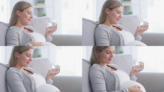 年轻孕妇在家里沙发上休息时喝水