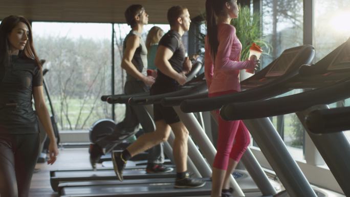 年轻的运动男女在运动健身房的跑步机上锻炼