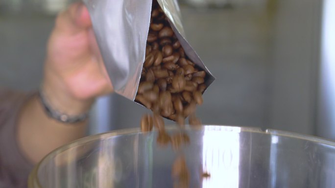 从袋子里倒咖啡豆咖啡豆倒入大缸玻璃缸