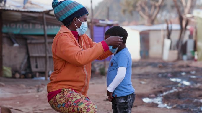 母亲给儿子戴口罩非洲难民贫困地区南非人民