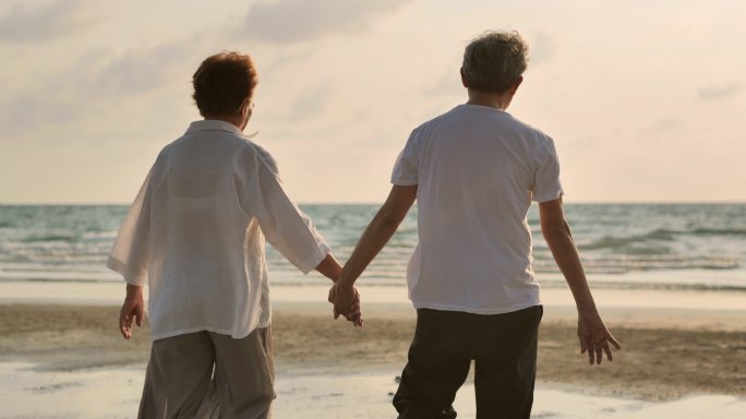 快乐的老年夫妇伸出援助之手，走向日落。