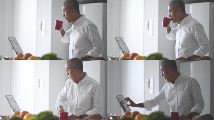 老人在厨房柜台边喝咖啡边用数码平板电脑