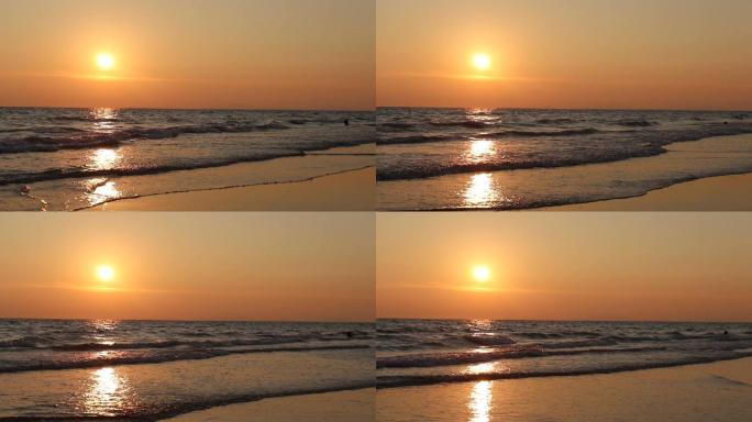 海滩上的海浪伴随着天空橙色的光