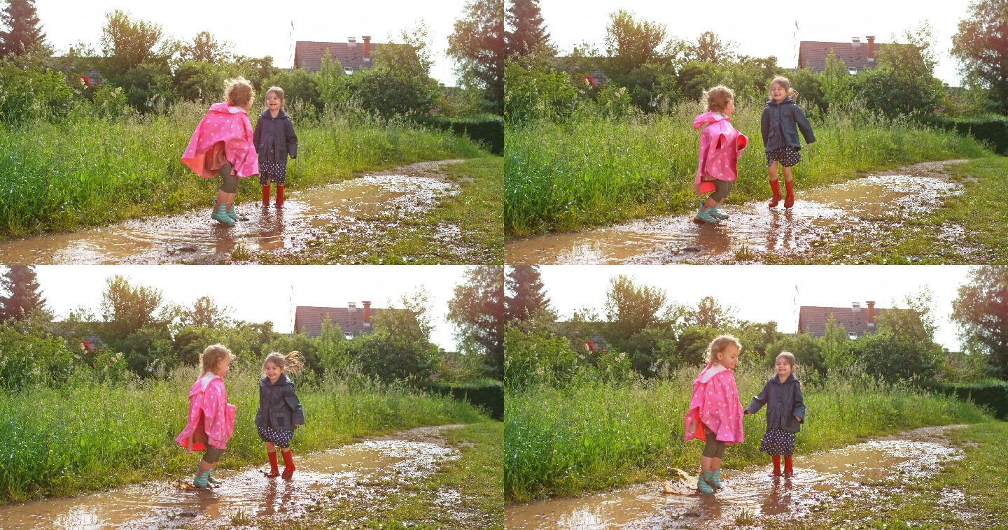 两个小女孩穿着雨靴在泥泞的水坑里跳