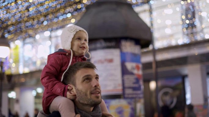 小女孩在爸爸背上欣赏圣诞灯
