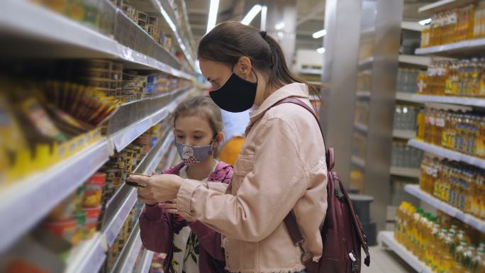 一名妇女带着女儿在超市里戴着医用防护面具