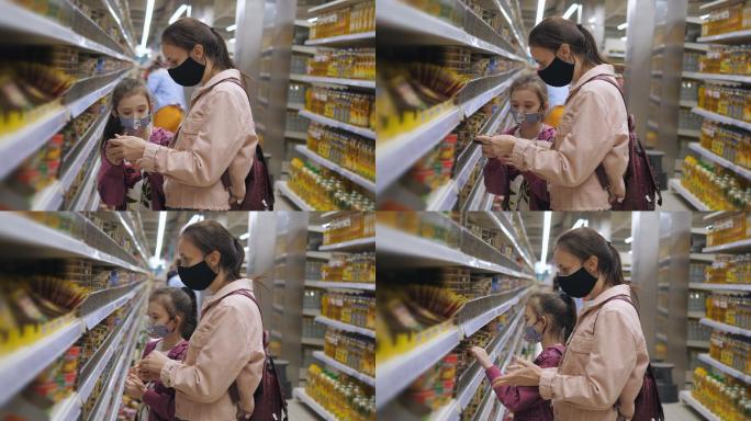 一名妇女带着女儿在超市里戴着医用防护面具