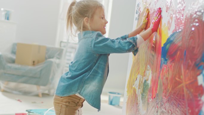 小女孩用手蘸着鲜艳的颜料在墙上画