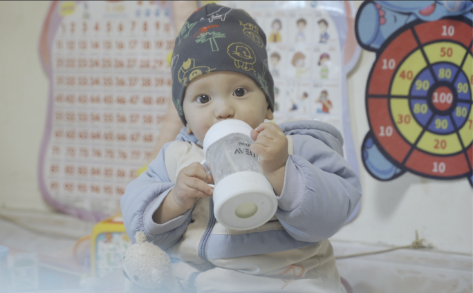 婴儿喝奶瓶，小奶娃拿着奶瓶进食，婴儿笑脸