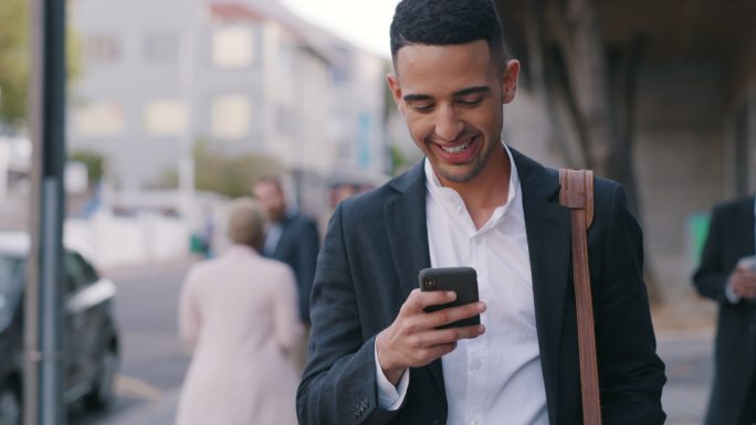 一个年轻商人在城市里行走时使用智能手机