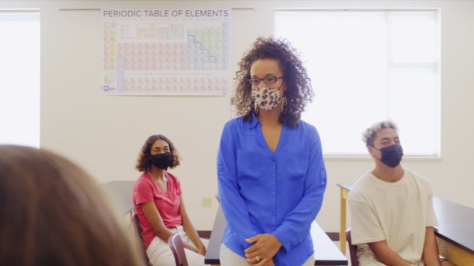 高中老师和学生在教室里戴着防护面罩