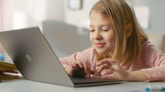 可爱的小女孩使用笔记本电脑。