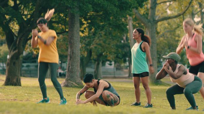 一组年轻女性在公园锻炼时做跳蹲