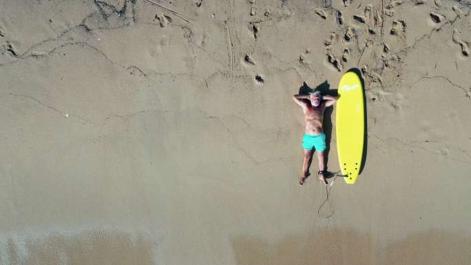 一位资深冲浪者在沙滩休息的鸟瞰视频