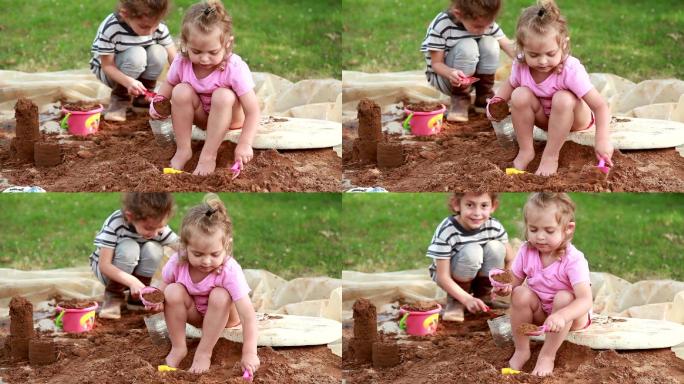 两个小女孩坐在一堆沙子上在做沙堡