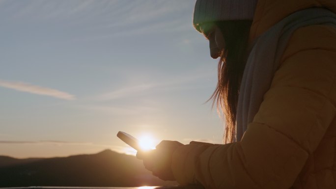 使用手机的女性山顶玩电子产品夕阳日出聊天