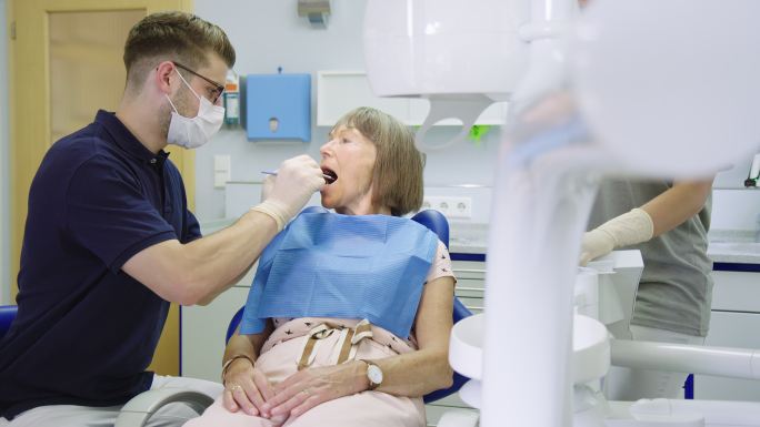 牙科医生在门诊检查老年患者的牙齿