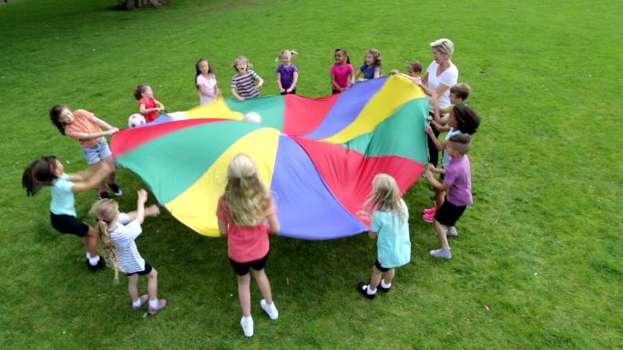 用降落伞玩球类游戏的孩子们