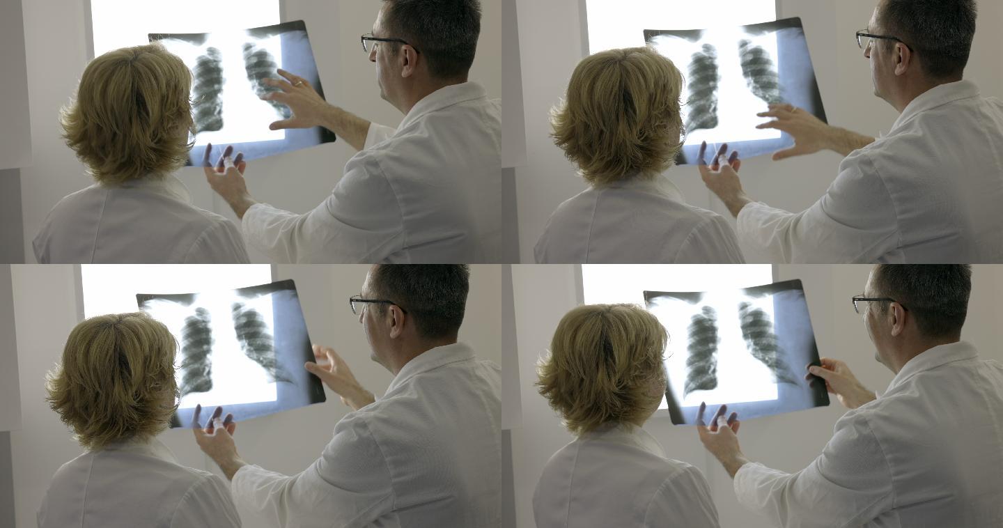 女医生和她的同事在窥镜上检查X射线的后视图
