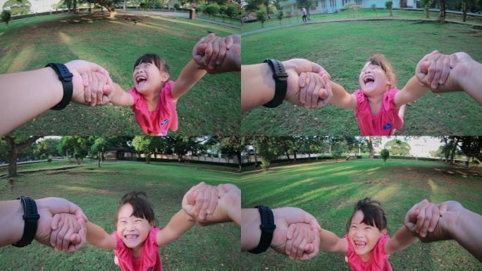 一位父亲抱着女儿在公园里转来转去的慢镜头
