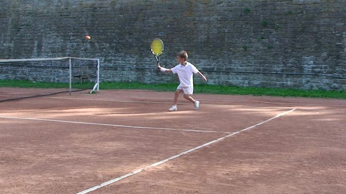 男孩在练习网球小朋友儿童球场