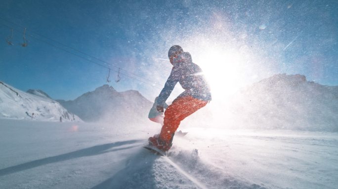 滑雪板运动员在阳光下沿着滑雪道滑行