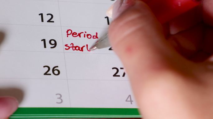女性用红笔在日历上手写经期提醒