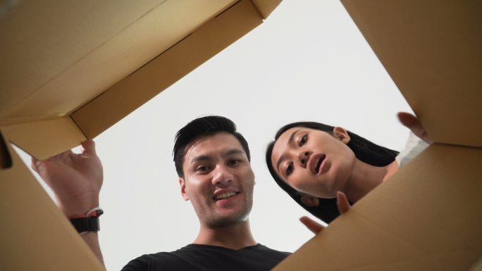 一对微笑的年轻夫妇打开一个纸箱往里看