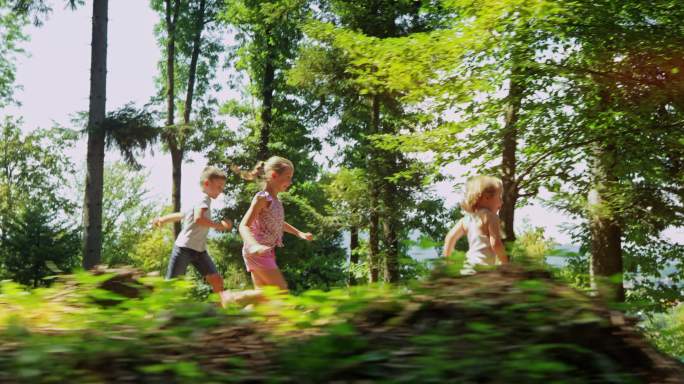 三个孩子从阳光明媚的山上跑下来