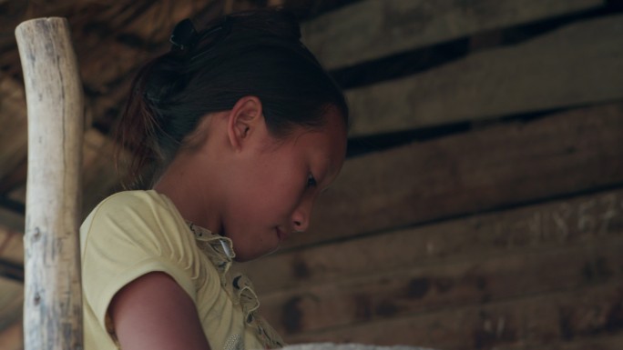 老挝农村的小女孩用石磨磨豆子