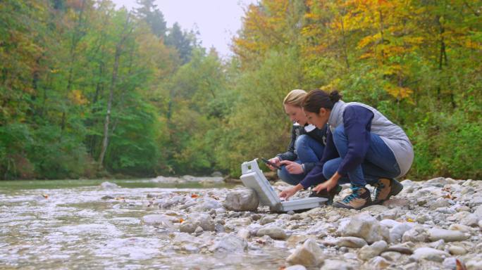 两名女生物学家正在从河里采集样本