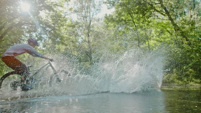 山地自行车手在森林中穿越小溪时溅水
