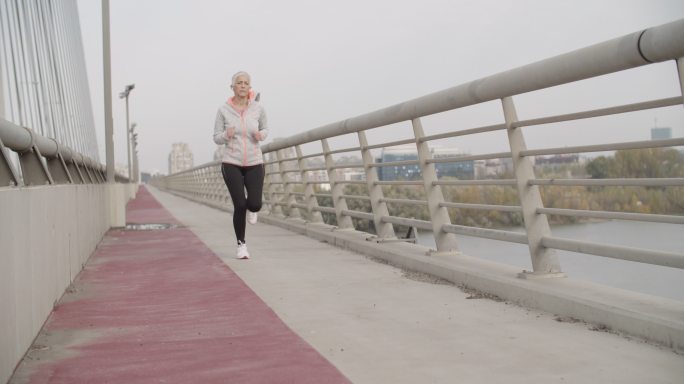 一个女人早上在城市的桥上跑步