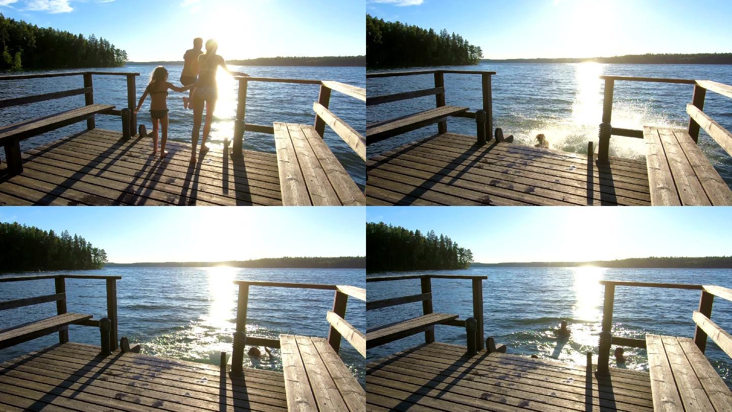 夫妇带着女儿在木码头上奔跑跳入湖中