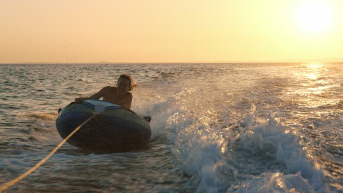 一个人在日落时乘坐充气管横渡大海的慢动作