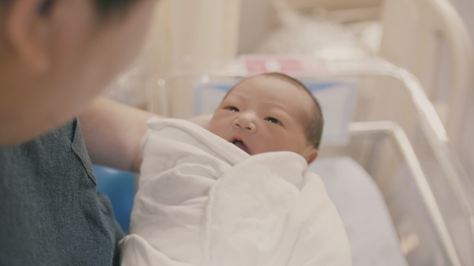 父亲抱着新生儿（0-1个月）站在育婴室