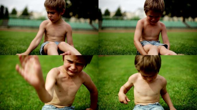 一个小男孩坐在草地上哭泣