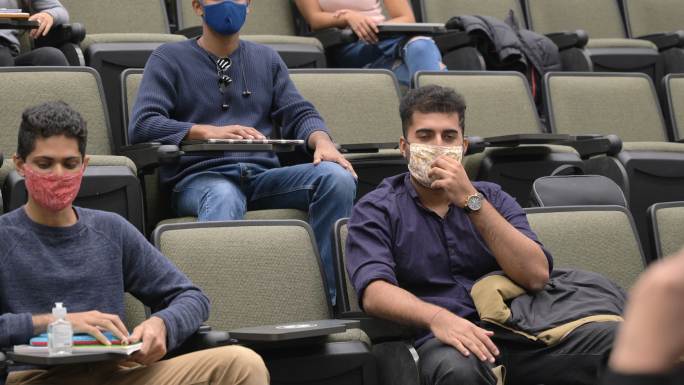 在演讲大厅里戴口罩的大学生