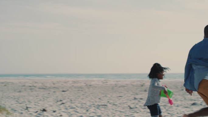 一个英俊的年轻人在海滩上和他的女儿玩接球