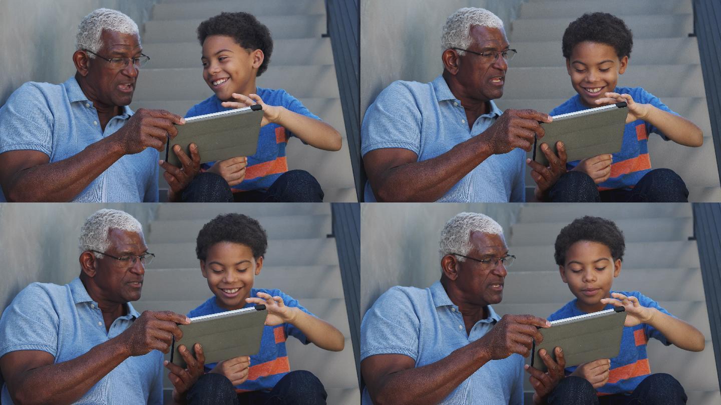 祖父和孙子坐在家门口使用平板电脑