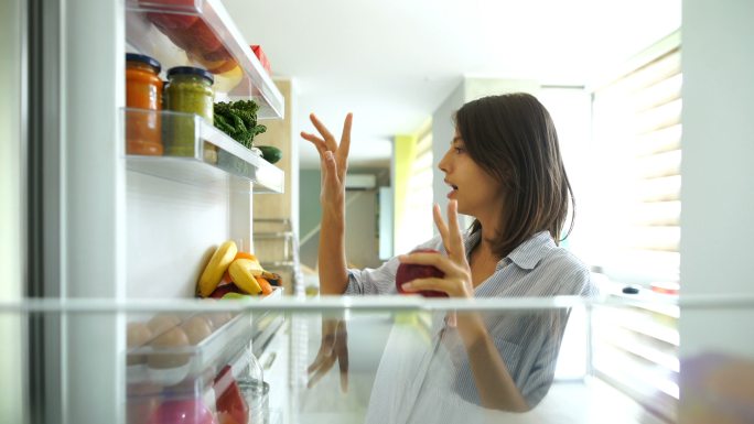 从冰箱里拿水果和蔬菜的女人。