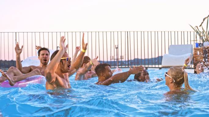 落日时分，游泳池派对上的人们在水中跳着舞