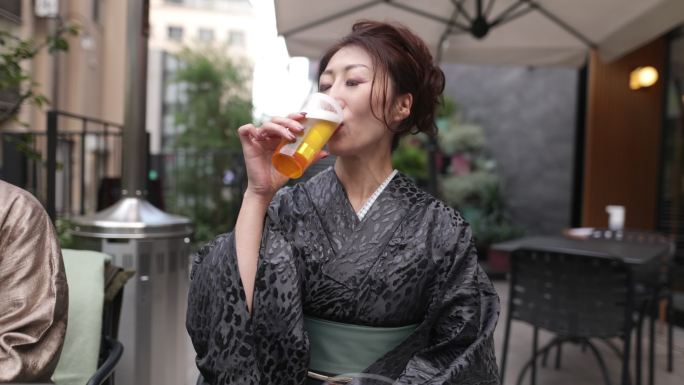 穿着和服的日本妇女在户外咖啡馆喝啤酒