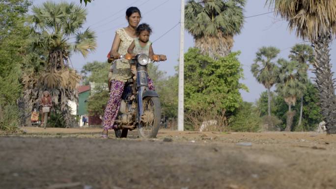 柬埔寨农村骑摩托车带孩子的女人