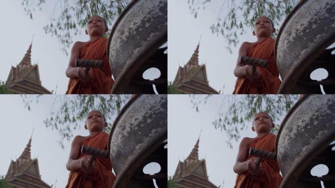 柬埔寨农村寺庙的小和尚在敲钟