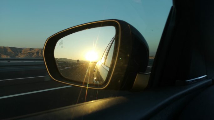 后视镜中的日落驾驶开车方向盘定位行驶导航