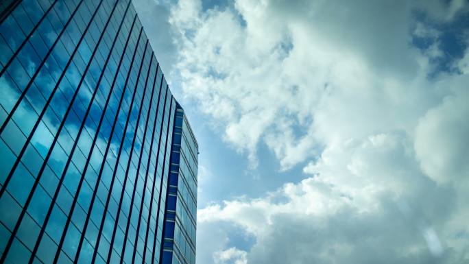 云层移动的天空反射在办公楼的玻璃窗上